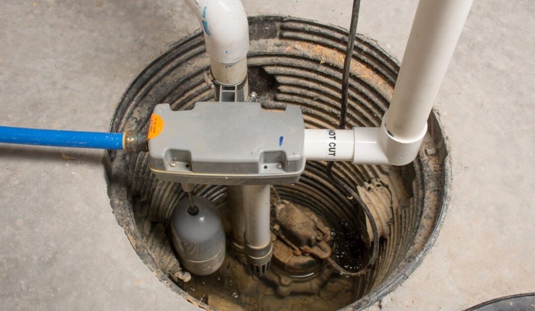 A sump pump system drains water through white PVC pipes inside a circular basement pit in a concrete floor.